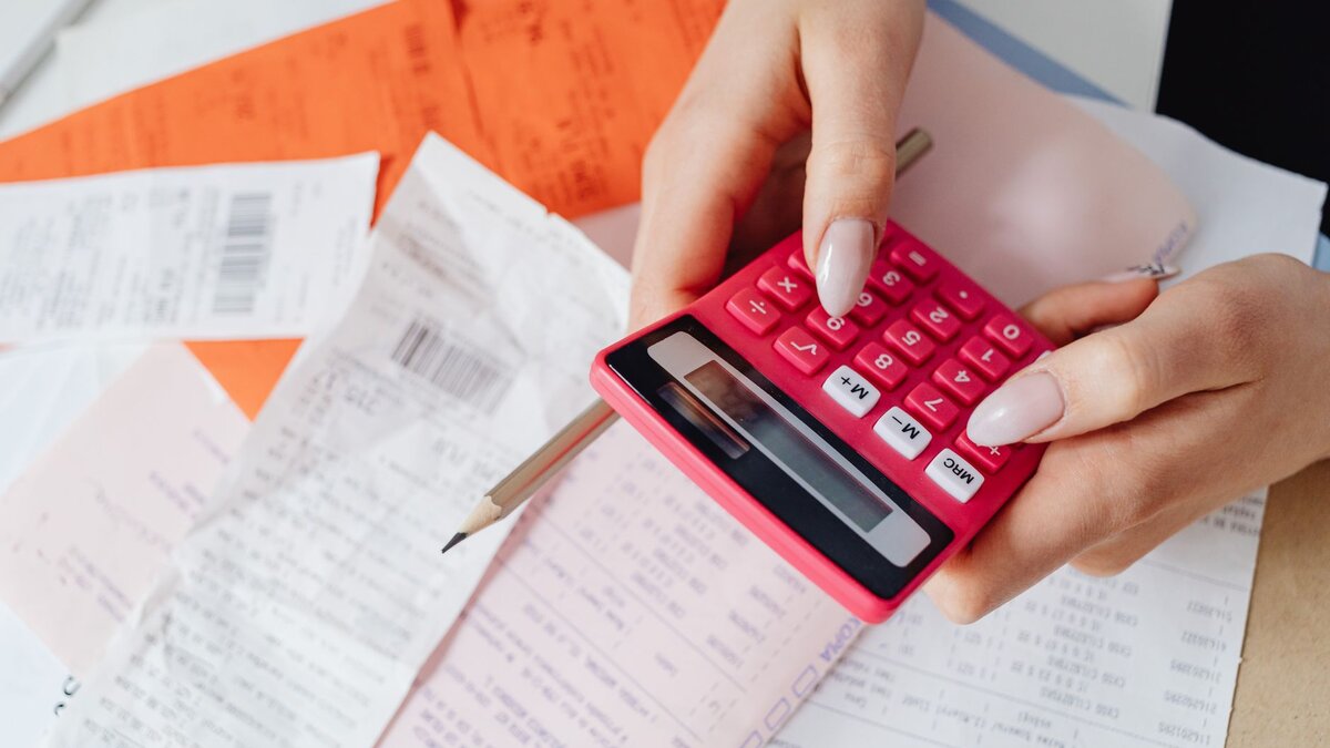Nota fiscal e calculadora sobre uma mesa de trabalho, representando o cálculo de tributos de uma empresa.